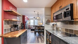 A modern kitchen with a wooden countertop, stainless steel appliances, and a dining area with a table and chairs. - Winter Park Resort Lodging - Convenient Condos (Winter Park)