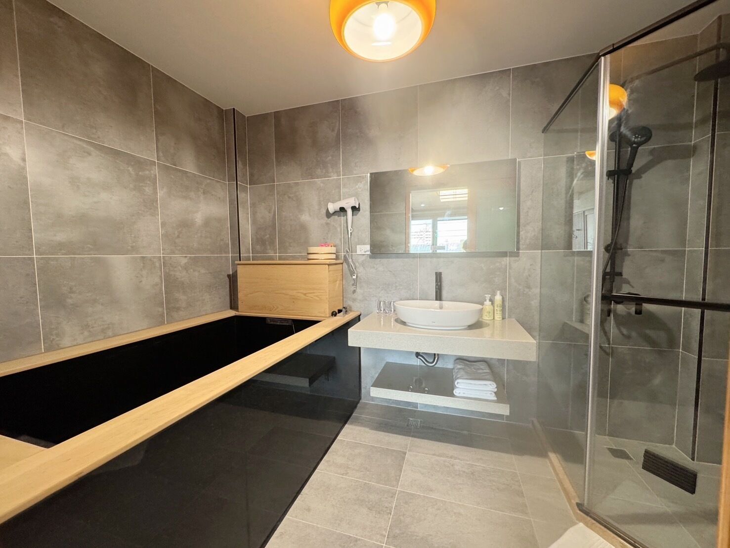 Ein modernes Badezimmer mit einer freistehenden Badewanne, einer Duschkabine und einem Waschtisch mit Waschbecken und Spiegel.