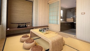 A traditional Japanese-style room with tatami flooring, a low wooden table, and a sliding glass door leading to a bathroom. - yado B&B (Chaozhou)