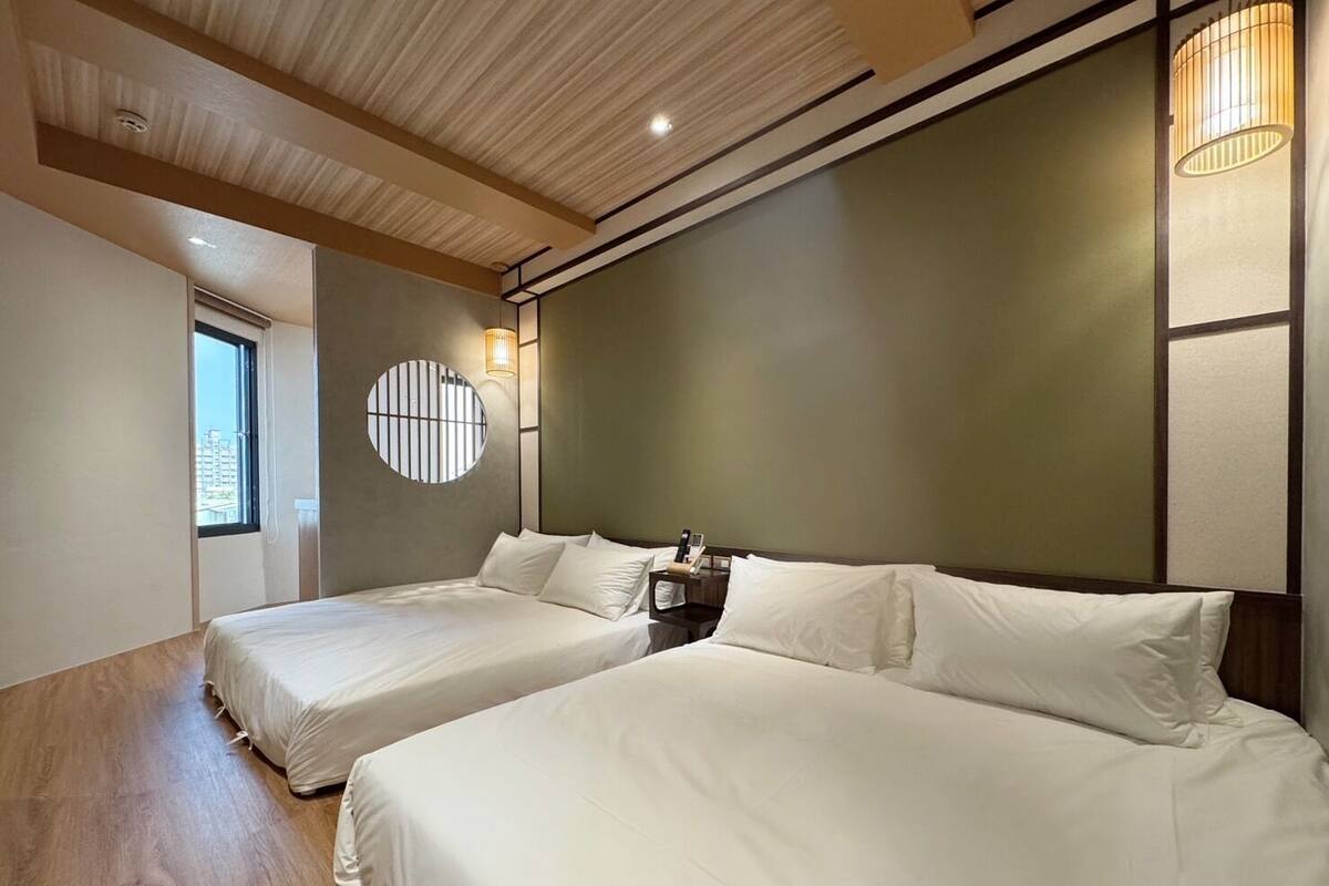 Une chambre d’hôtel avec deux lits, une fenêtre ronde et un plafond en bois.