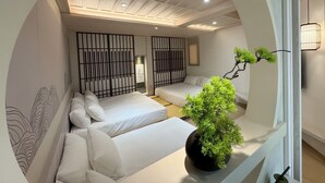 A modern bedroom with two beds, a large potted plant, and a view through an arched window. - yado B&B (Chaozhou)