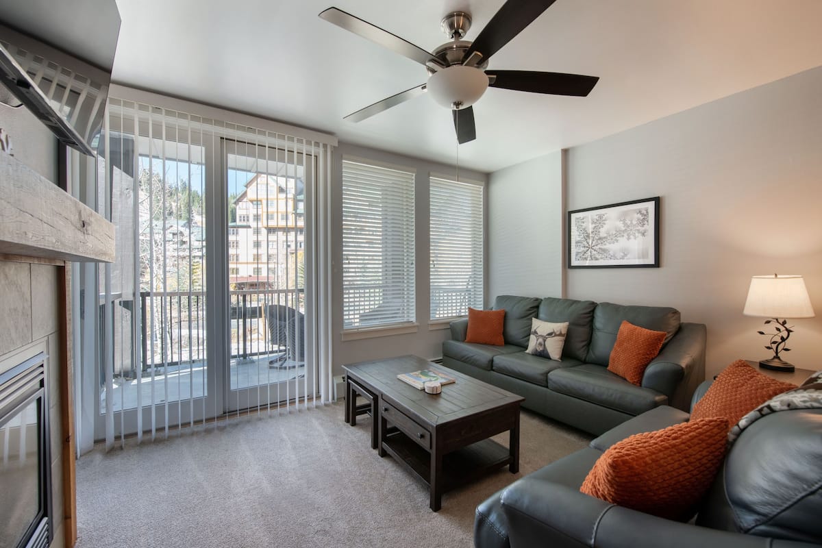 A living room with a sofa, coffee table, and a ceiling fan.