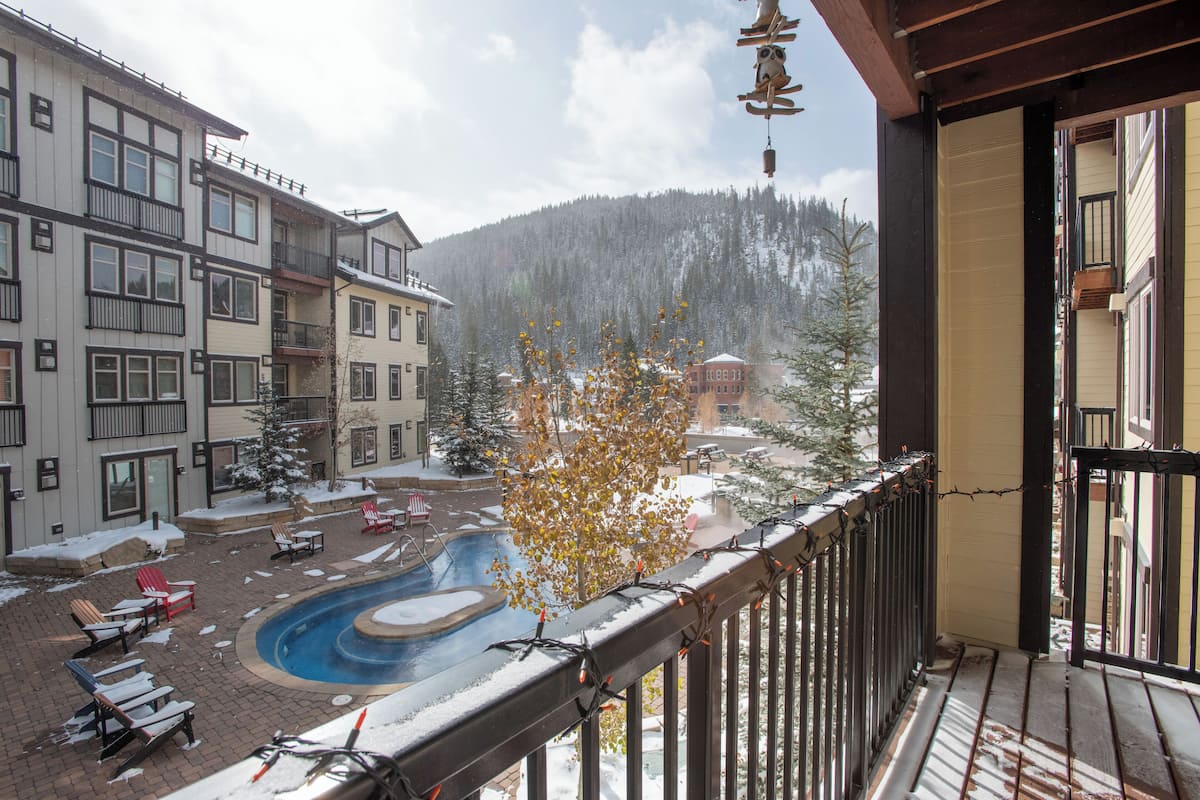 A pool area with lounge chairs and a snow-covered landscape in the background.
