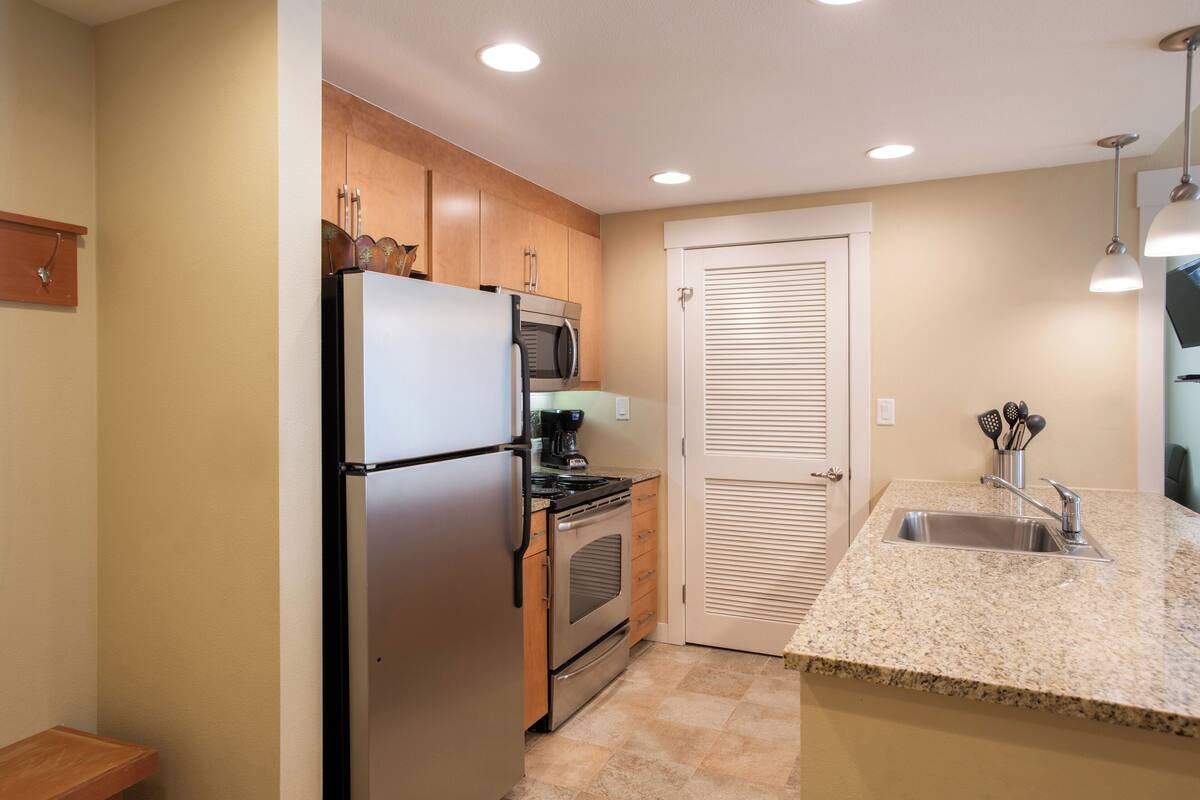 A compact kitchen with a refrigerator, stove, microwave, and a sink.