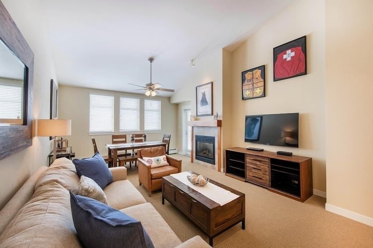 A living room with a sofa, coffee table, TV, fireplace, and framed pictures on the wall.
