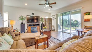 A spacious living room with a large sofa, a television, and a fireplace. There is a sliding glass door leading to a patio area. - 5 Mi to Dtwn Clermont: Family Home w/ Water Views! (Clermont)