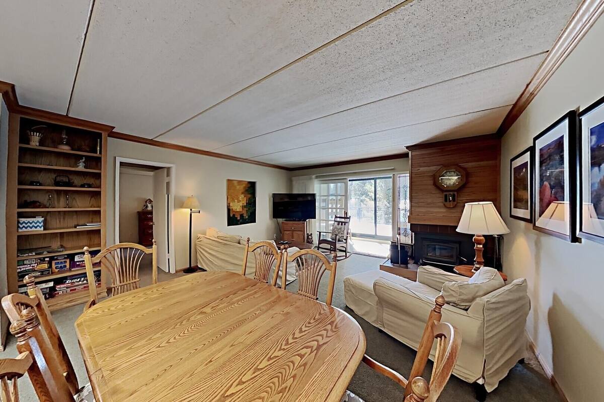 A cozy living room with a wooden dining table, a sofa, and a fireplace.