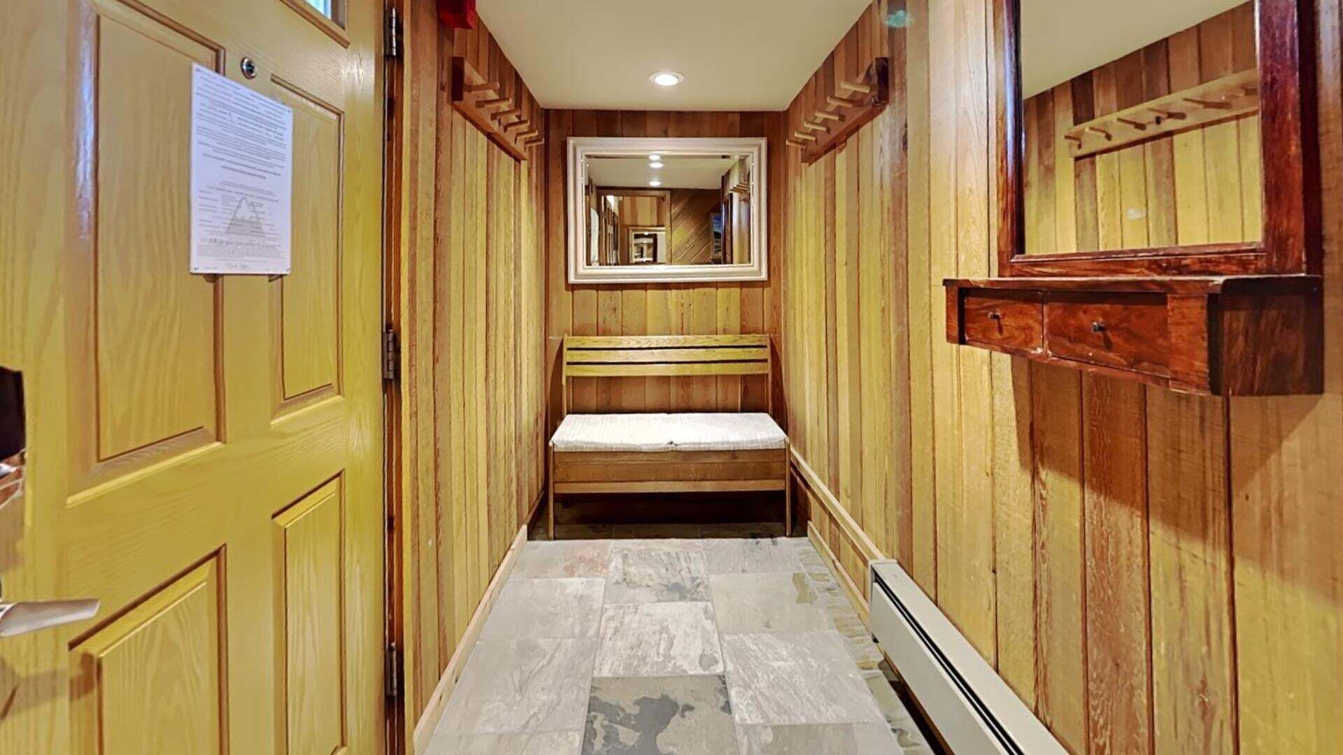 Un pasillo estrecho con paneles de madera, un banco y un espejo en la pared.