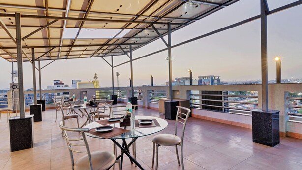 Eine Dachterrasse mit Tischen und Stühlen, einer Glasumlaufung und Blick auf die Stadt.