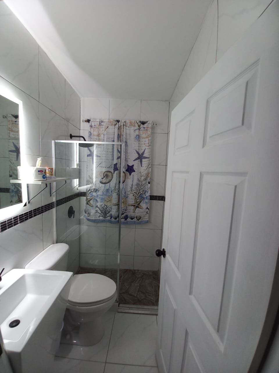 A small bathroom with a toilet, sink, and shower.