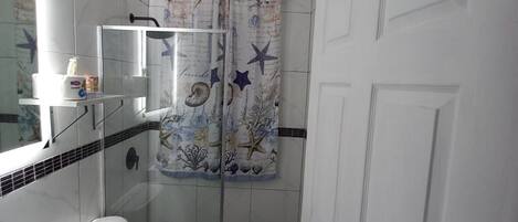 A small bathroom with a toilet, sink, and shower.
