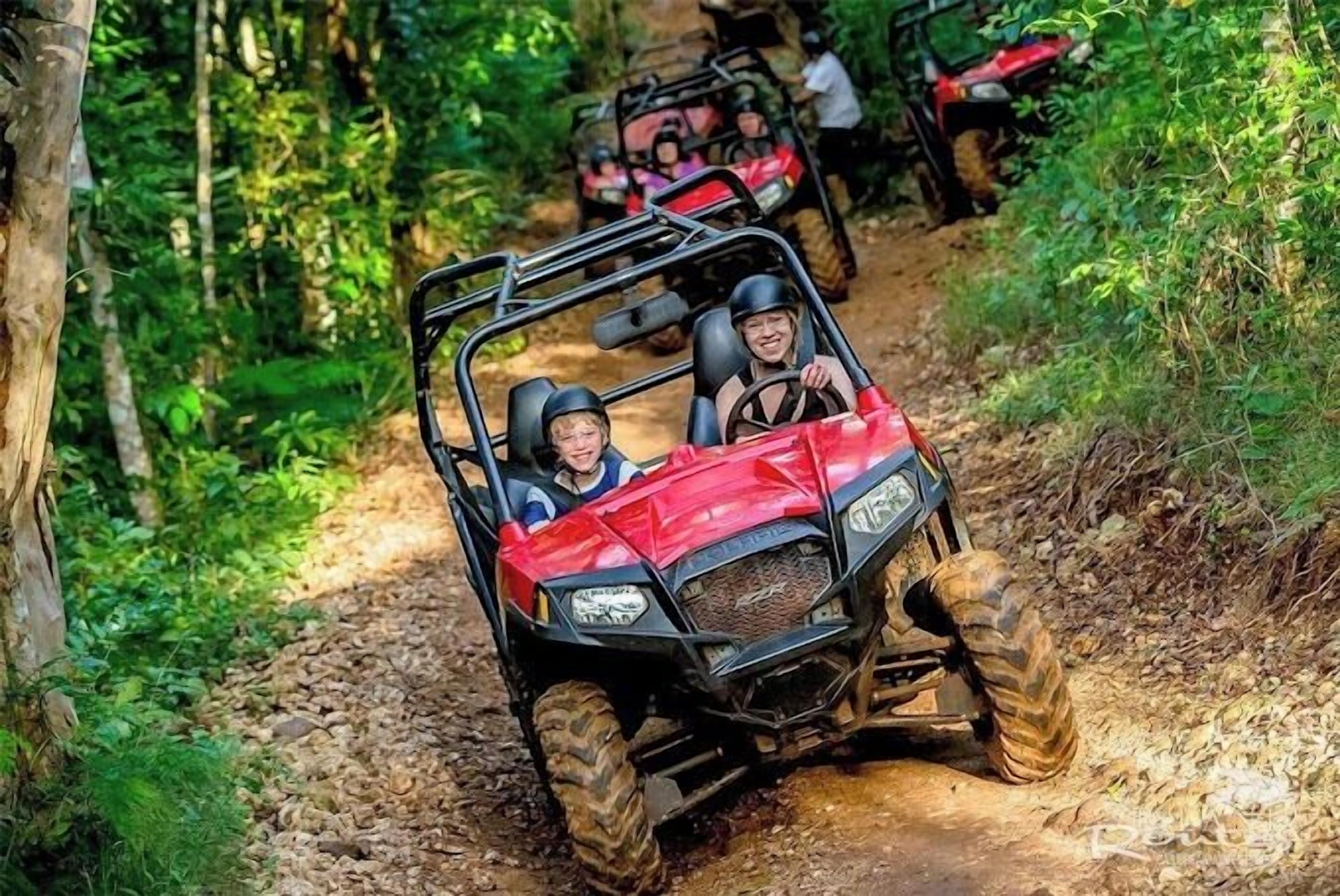 A red off-road vehicle on a dirt path surrounded by greenery.