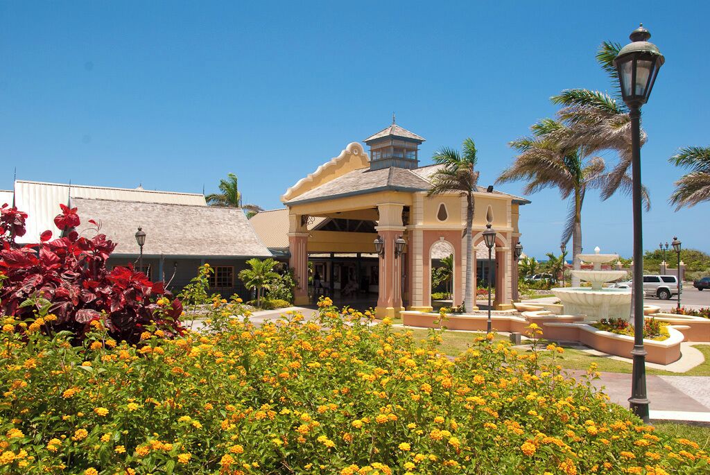 A building with a central pavilion, palm trees, and a fountain.