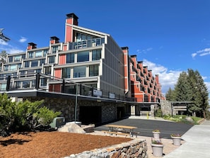 A modern multi-story hotel with a stone facade, large windows, and a covered outdoor area with a bench and potted plants. - Fantastic 3 Bedroom Condo with Great Views and Quiet Slopeside Location! 3 Condo (Mammoth Lakes)