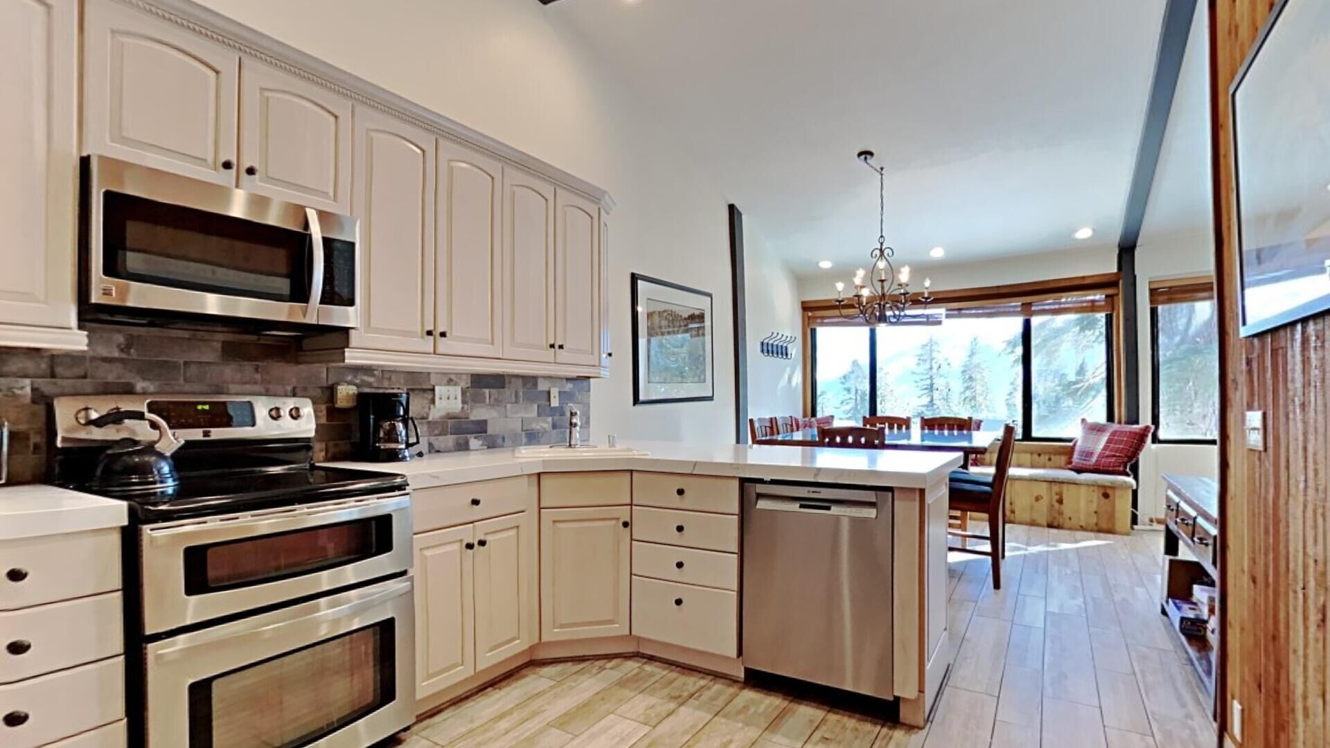 A modern kitchen with white cabinets, stainless steel appliances, and a large island.