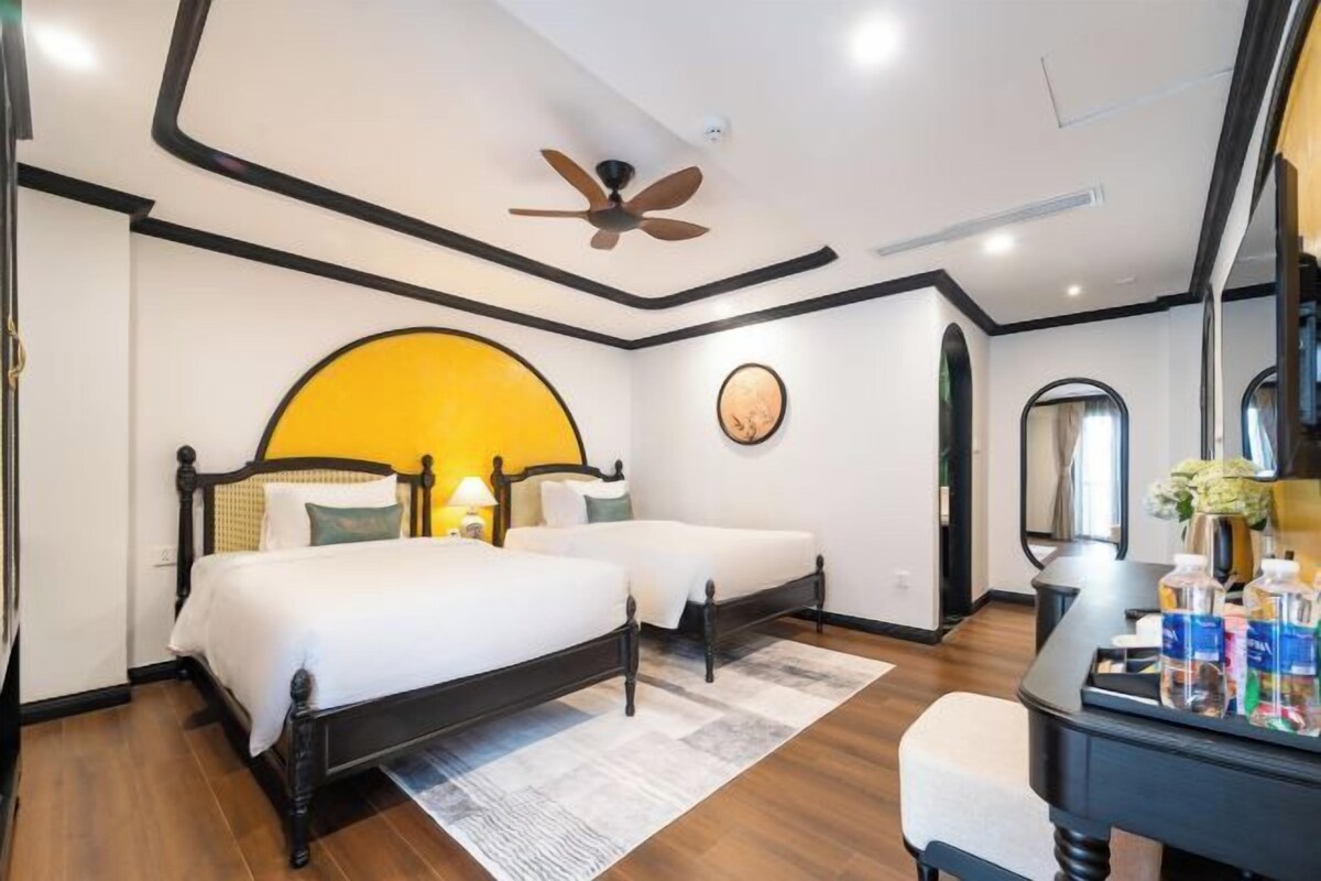 A hotel room with a bed, two bedside tables, a mirror, and a ceiling fan.