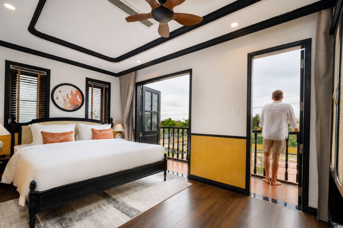 Un dormitorio con una cama grande, ventilador de techo y balcón con vistas.