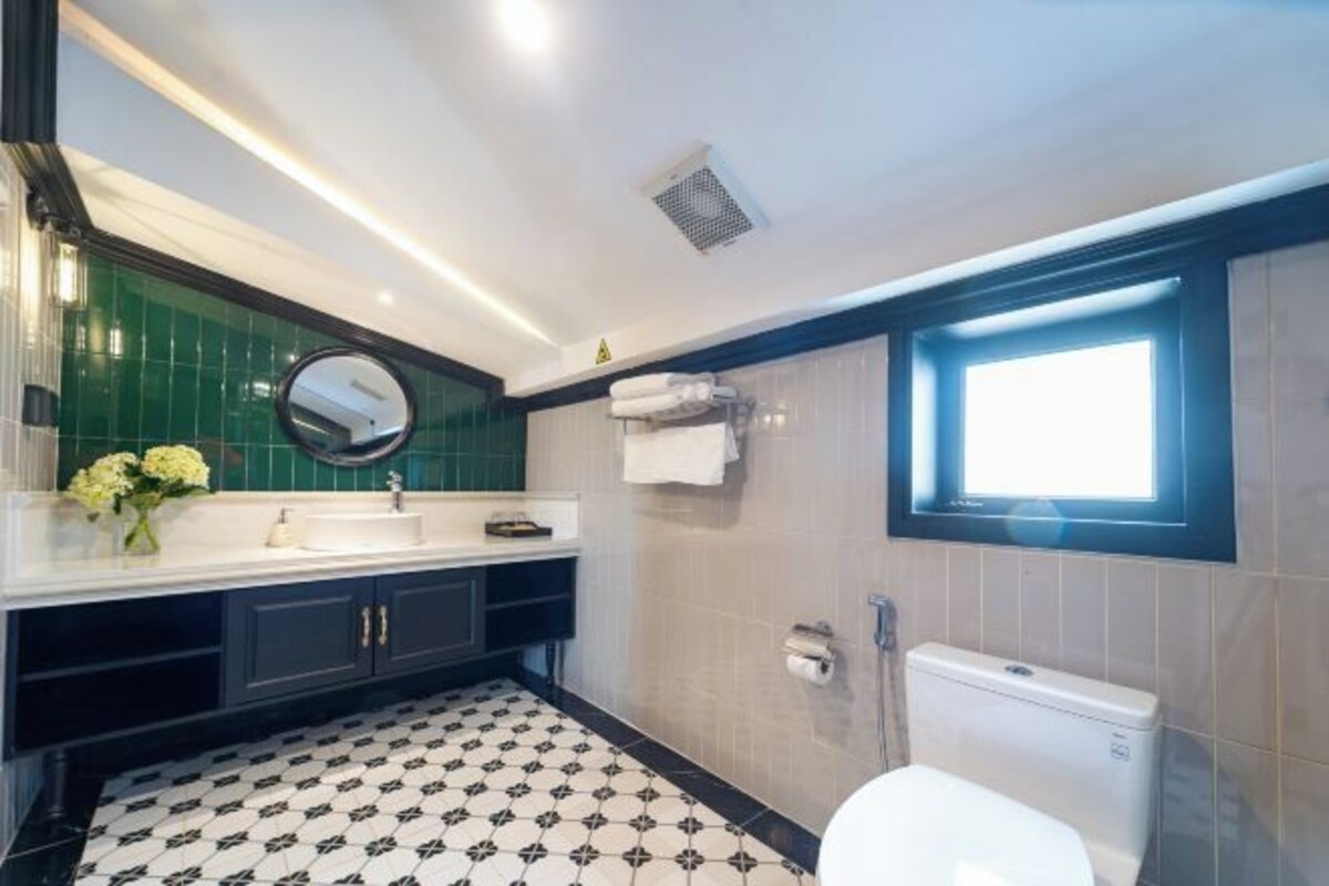 A bathroom with a black and white patterned floor, a white sink with a mirror, and a window above the toilet.