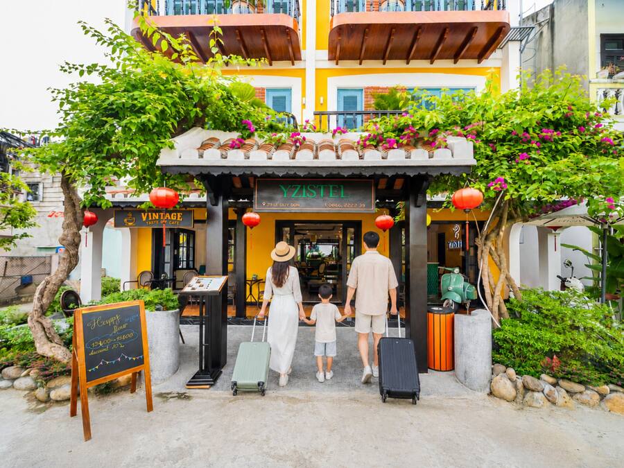 A family entering a building with a sign reading 'YZISTEL VINTAGE TASTE OF CAFE'.