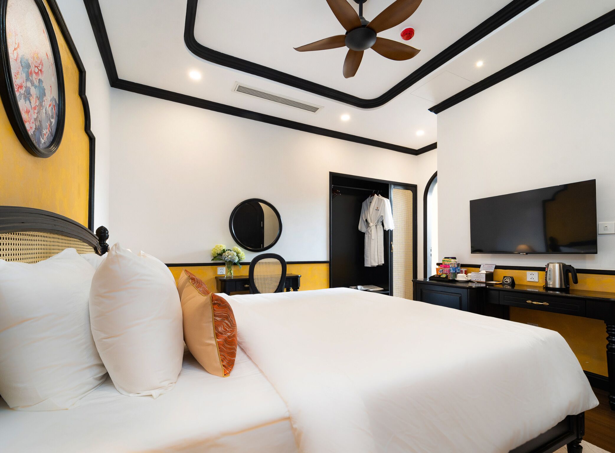 A hotel room with a bed, a desk, a television, and a ceiling fan.