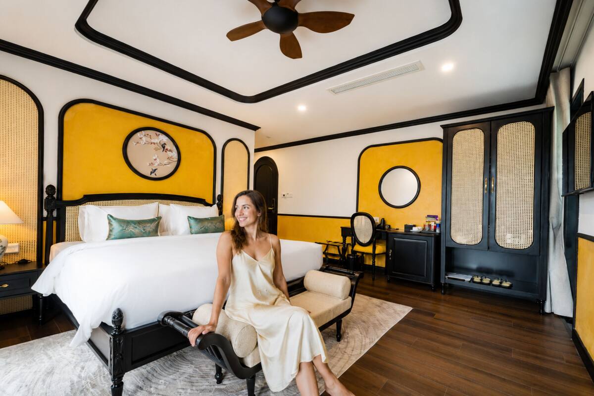 Un dormitorio con cama, zona de estar, ventilador de techo y reloj de pared.
