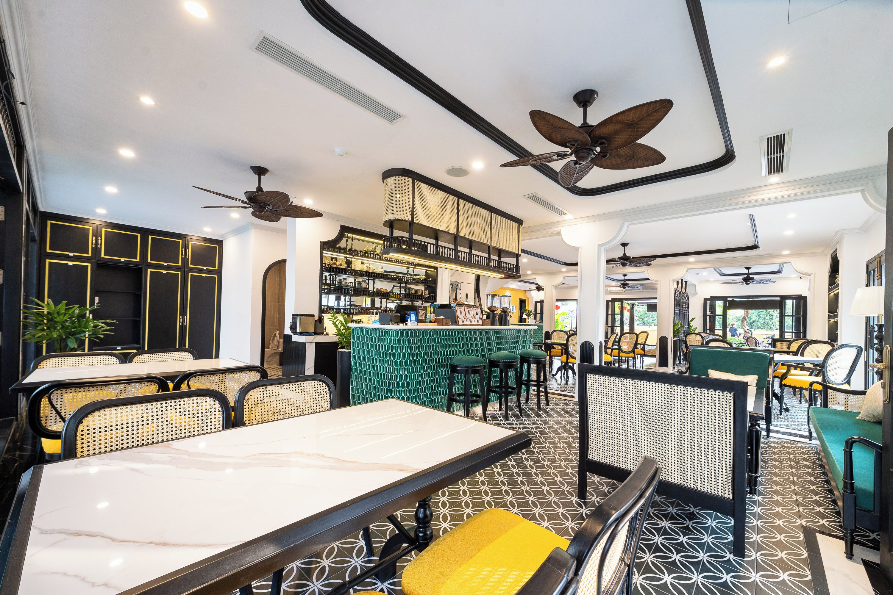 A modern restaurant with high ceilings, ceiling fans, and a bar area.