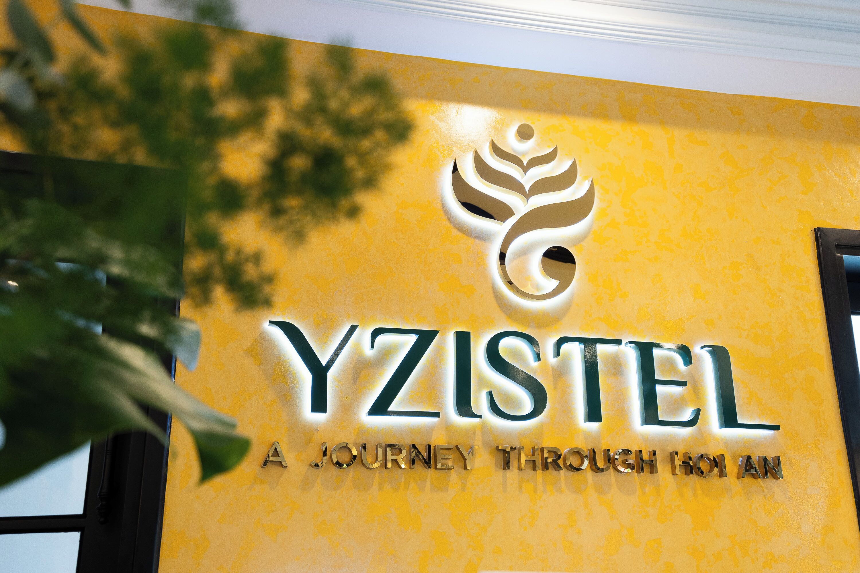 A hotel sign with the name "YZISTEL" and the tagline "A JOURNEY THROUGH HOU AN".