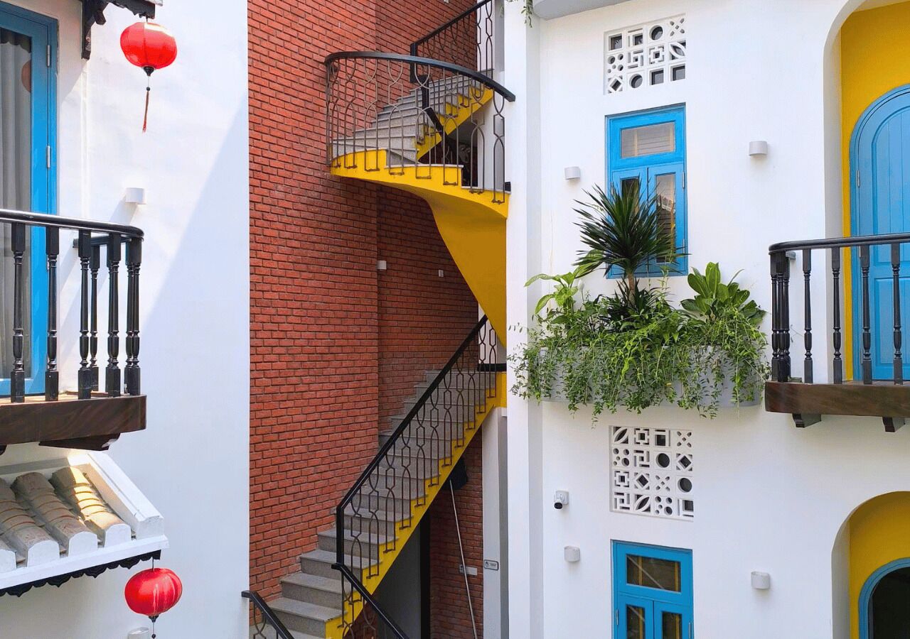 Un immeuble à plusieurs étages avec un escalier jaune, des portes bleues et des lanternes rouges.