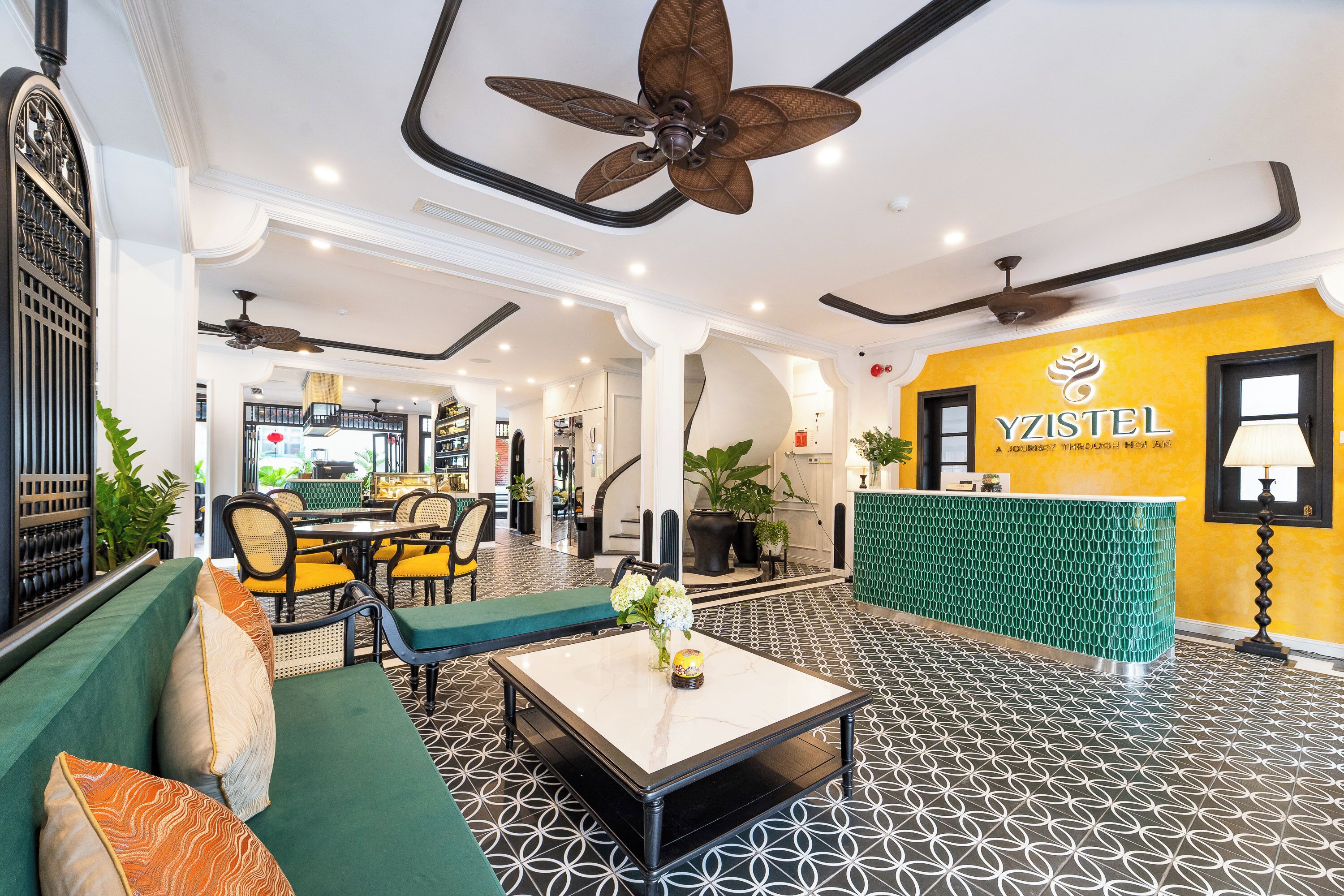 A hotel lobby with a reception desk, seating area, and ceiling fans.