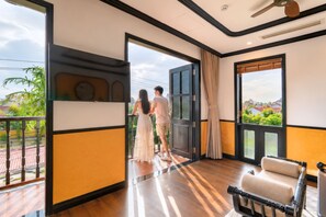 A room with a balcony, a large window, and a ceiling fan. - Yzistel Hoi An (Da Nang)
