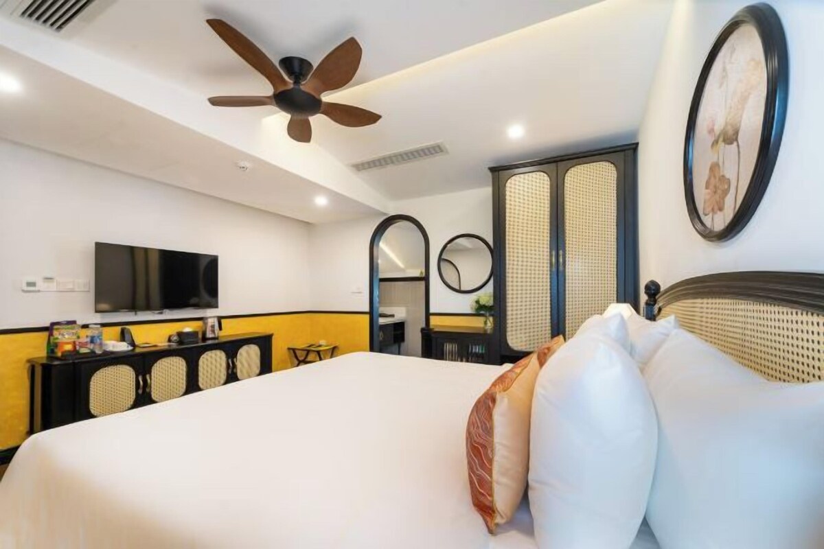 Ein Hotelzimmer mit einem Bett, einem Deckenventilator, einem Fernseher, einem Spiegel und einer Kommode.