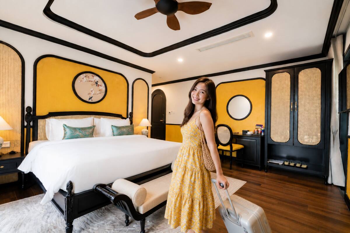 Un dormitorio con una cama, una maleta, un reloj de pared y un ventilador de techo.