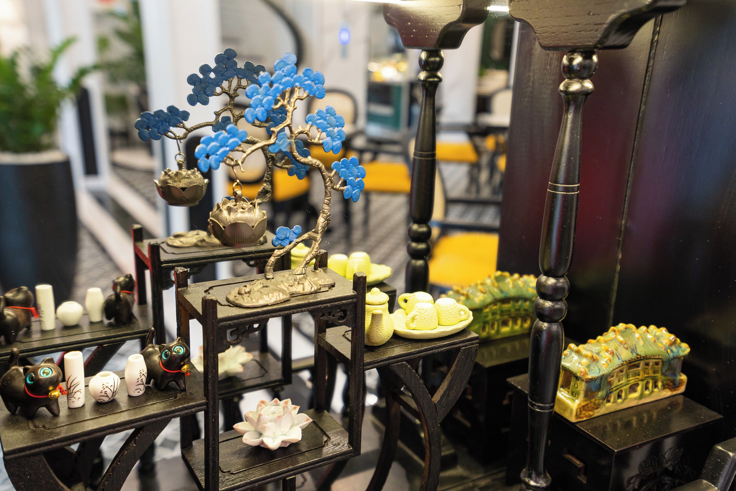 A display of various decorative items including ceramic figurines, a miniature house, and a tree with blue flowers.