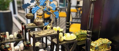 A display of various decorative items including ceramic figurines, a miniature house, and a tree with blue flowers.