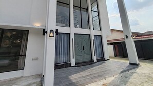 Un edificio moderno a due piani con ampie finestre e una porta verde ben visibile.