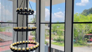 Un lampadario con più livelli di candele, ampie finestre con vista su spazi verdi e un'auto rossa all'esterno.