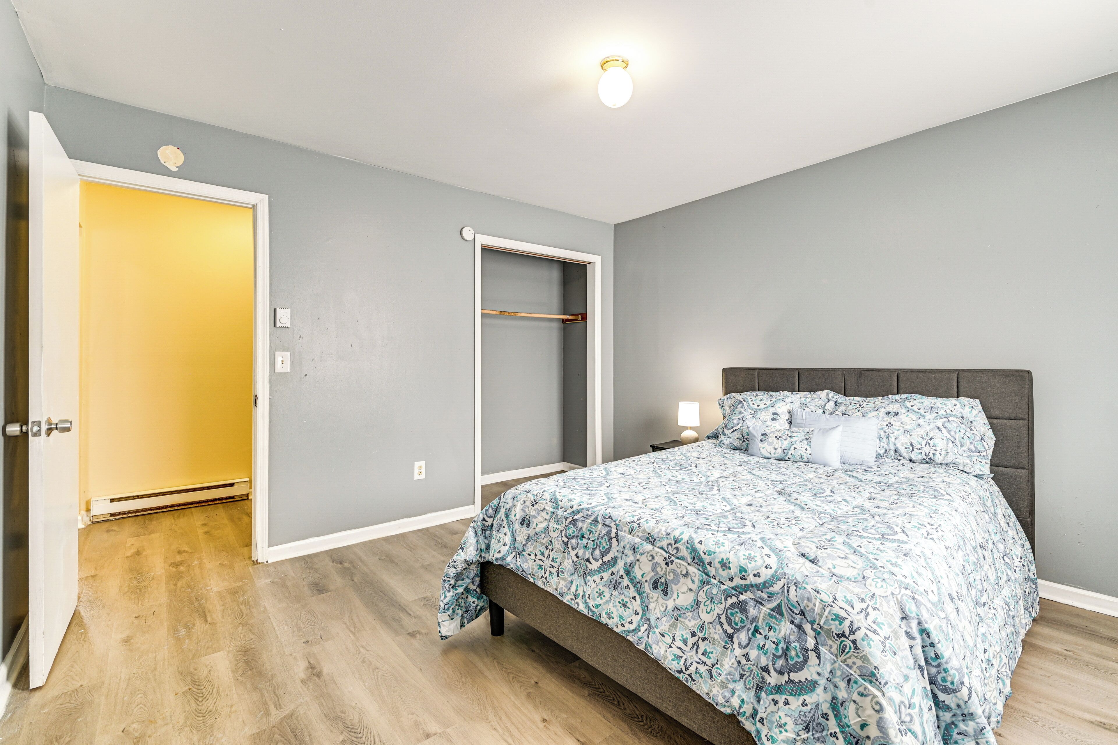 Une chambre à coucher comprenant un lit, une table de chevet, une commode, une armoire et une porte.