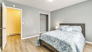 A bedroom with a bed, a nightstand, a bedside table, a wardrobe, and a door. - Near Hospitals: Home w/ Yard in Albany! (Albany)