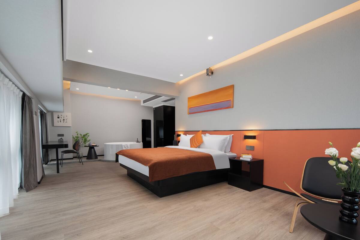 A modern hotel room with a large bed, a desk, and a chair.