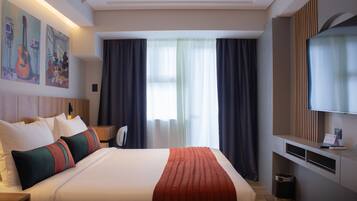 A modern hotel room with a large bed, a flat-screen TV, and artwork on the wall.
