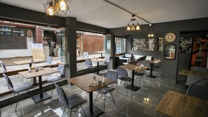 A modern restaurant interior with multiple seating areas, including tables and chairs, and a visible kitchen area. - SEMAY OTEL (Amasya)