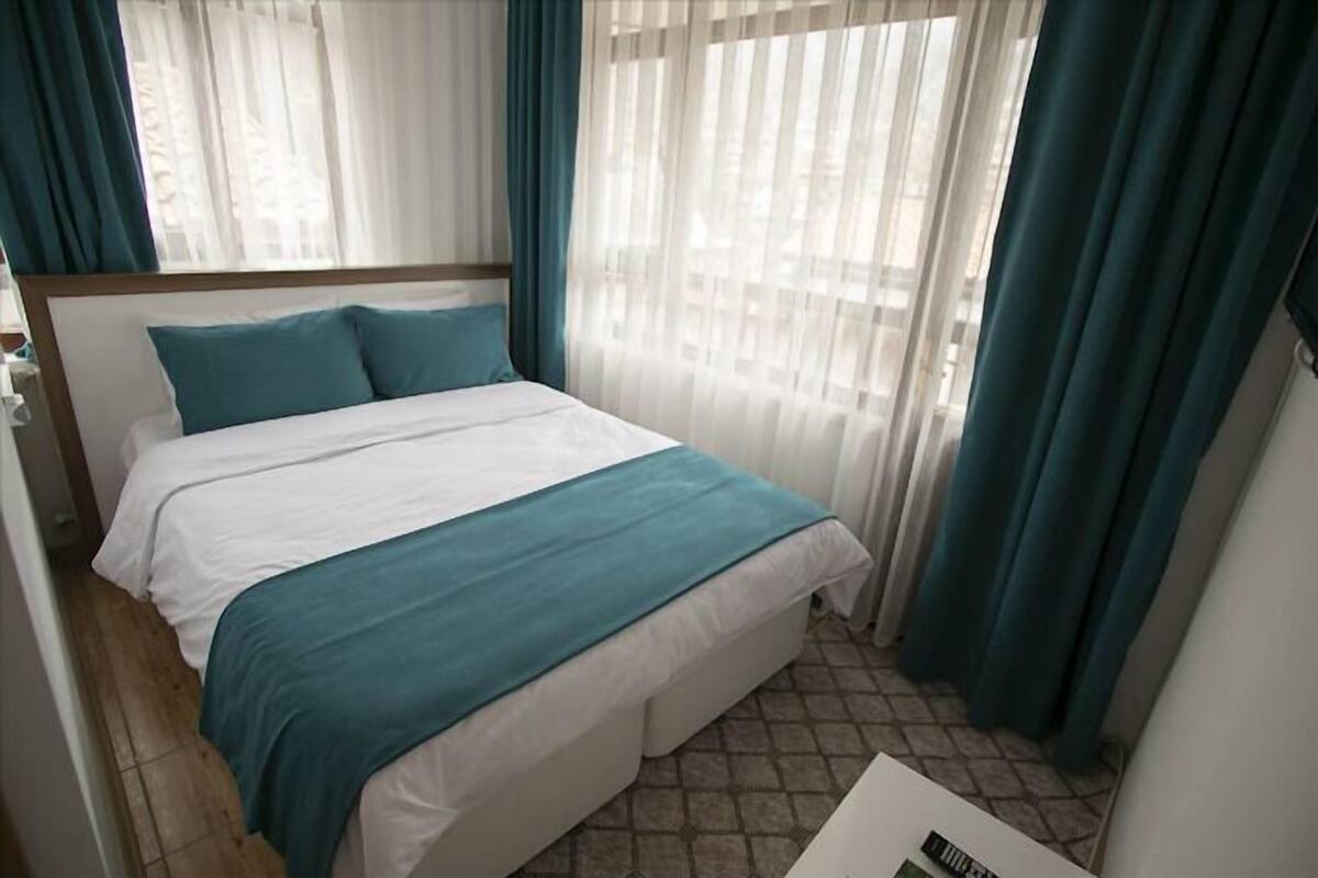 A hotel room with a bed, curtains, and a window.
