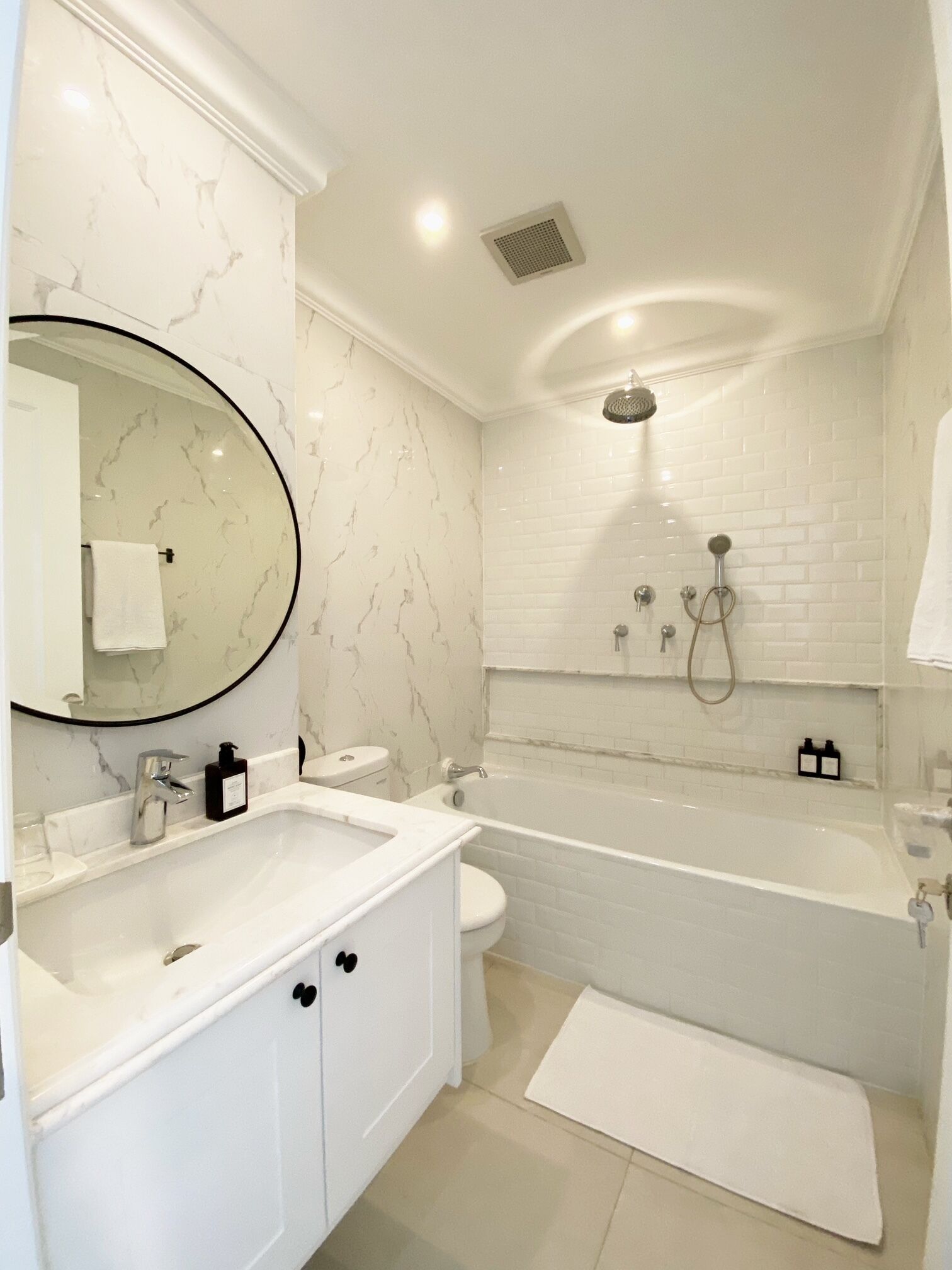 Ein modernes Badezimmer mit Waschtisch aus weißem Marmor, einer freistehenden Badewanne und einer Toilette.