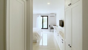 A hotel corridor with a bed, a TV, and a bathroom. - Loewy's Home Jakarta (Jakarta)