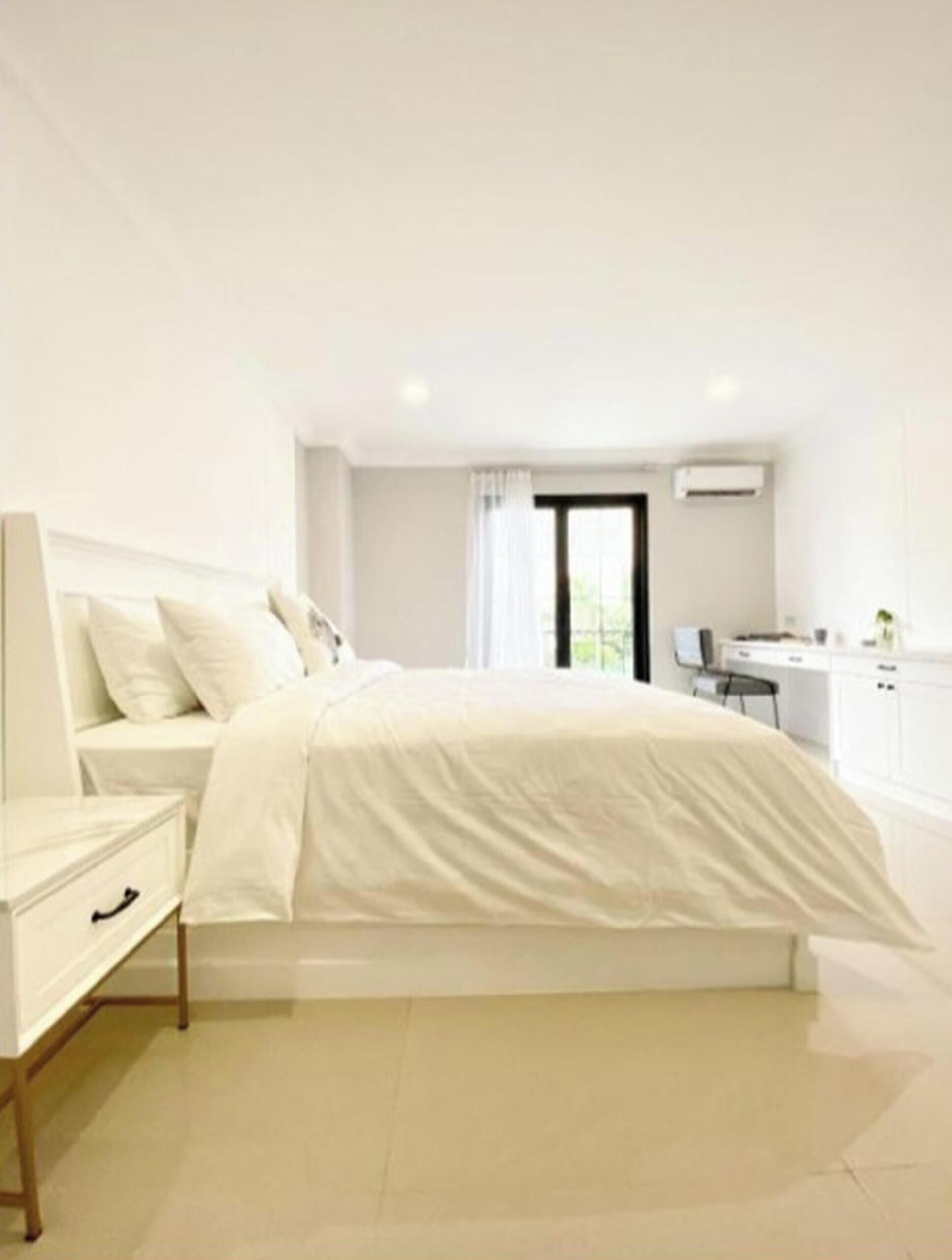 Un dormitorio moderno con cama, mesita de noche y vista a una zona de cocina.