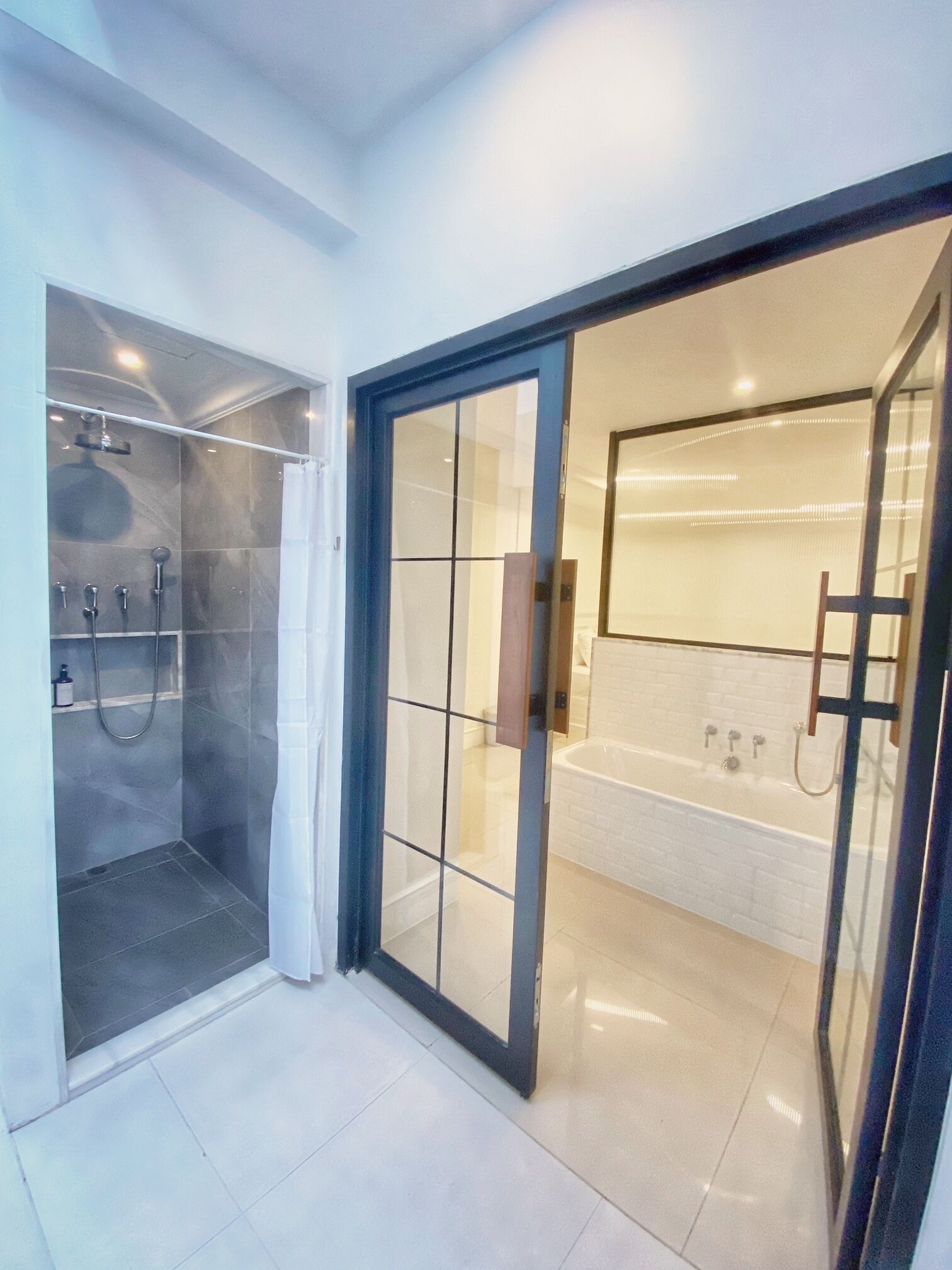Une salle de bain moderne dotée d’une douche à parois de verre, d’une baignoire et d’une porte en verre donnant accès à la douche.