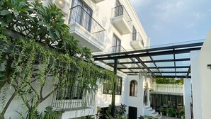 A courtyard with outdoor seating, potted plants, and a building with balconies. - Loewy's Home Jakarta (Jakarta)