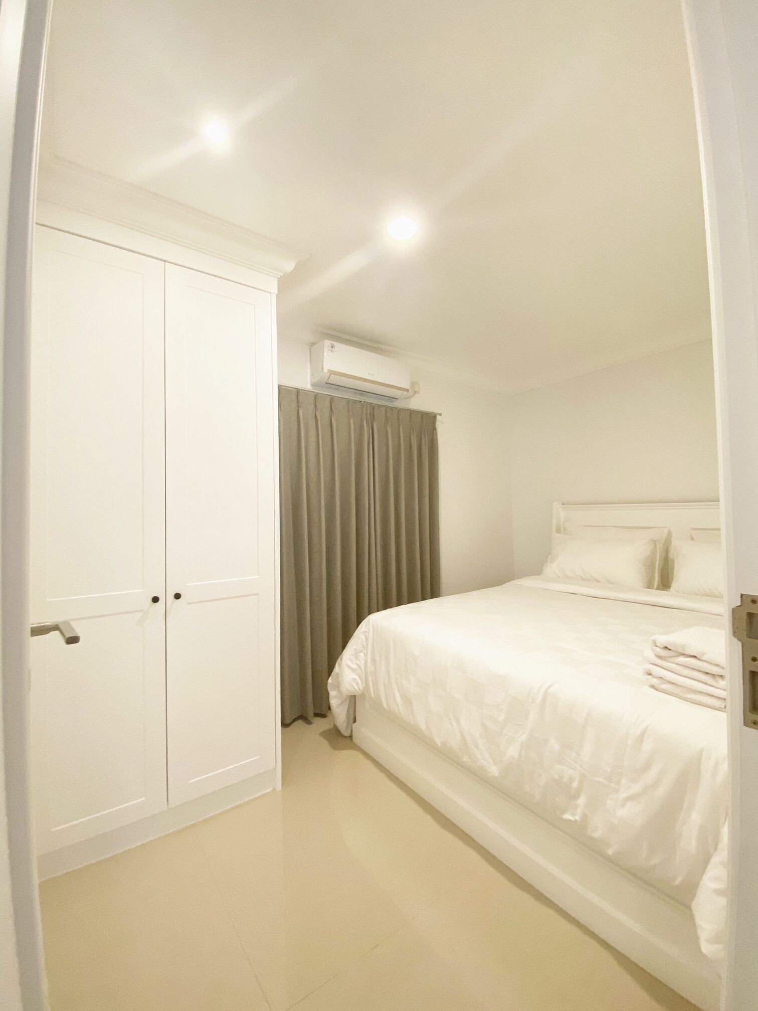 A bedroom with a bed, a wardrobe, and an air conditioning unit.