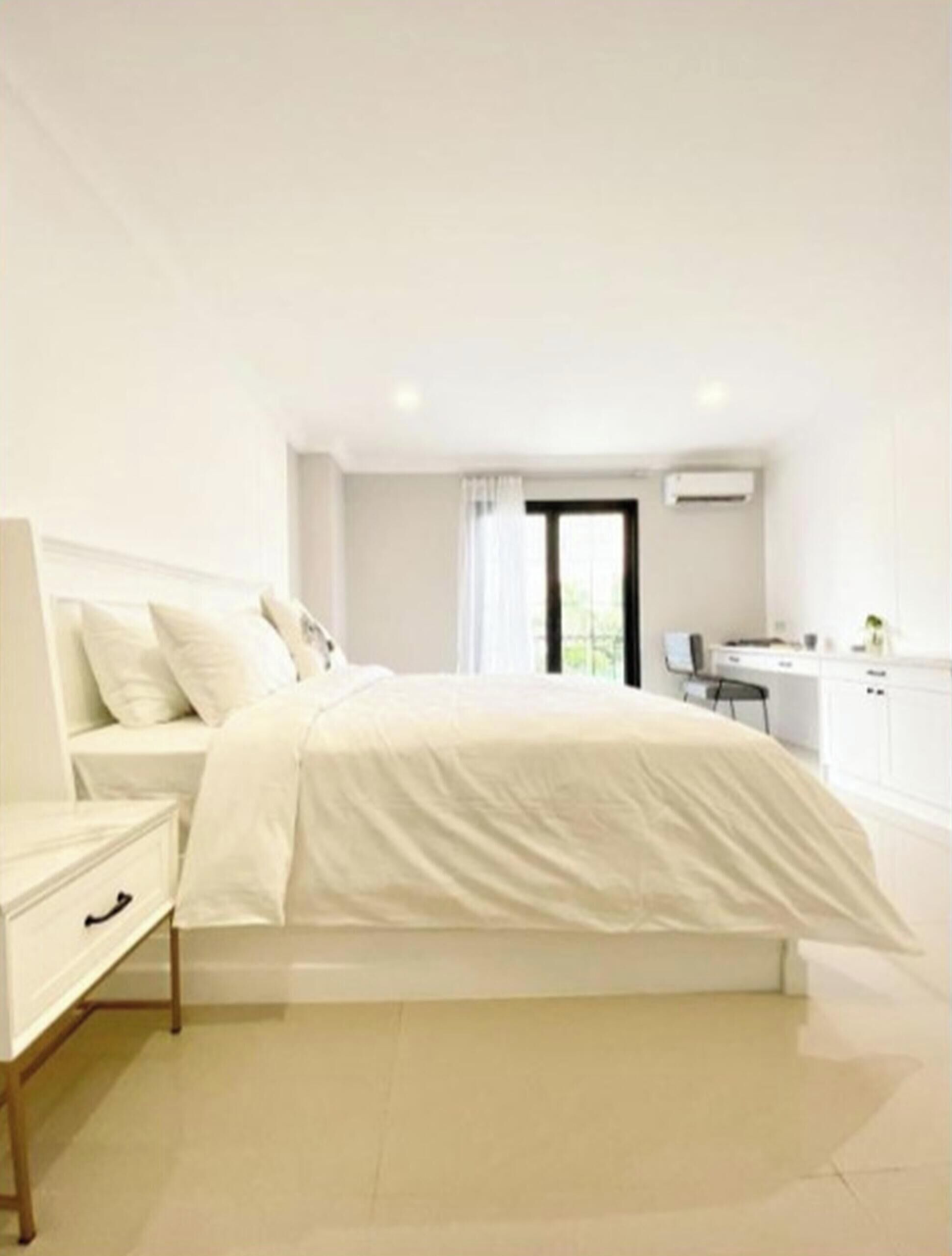 Un dormitorio moderno con cama, mesita de noche y vista a una zona de cocina.