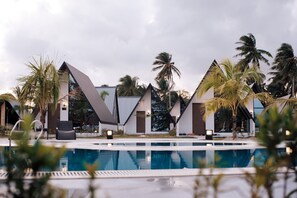 Een modern resort met een zwembad, palmbomen en eigentijdse gebouwen.